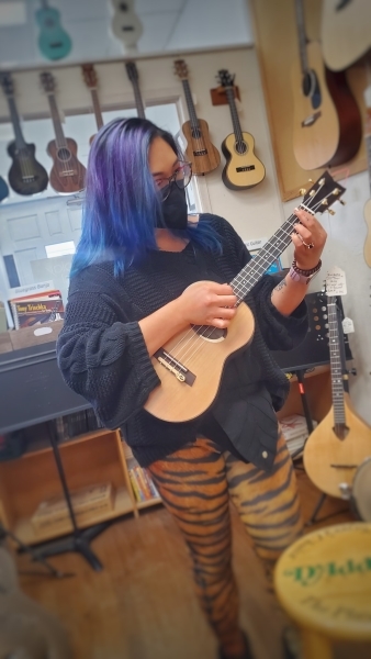 Woman with mask playing a ukulele at a music store