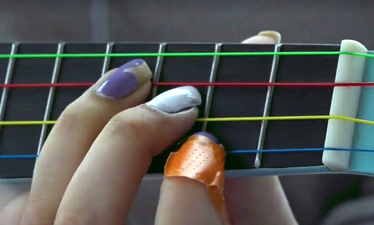 A child's fingers on the fretboard of a ukulele