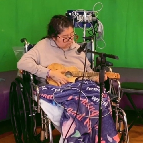 Child in a wheelchair holding a ukulele